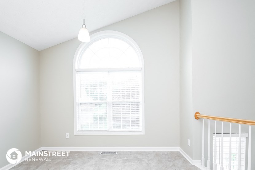 a living room with an arched window and a staircase