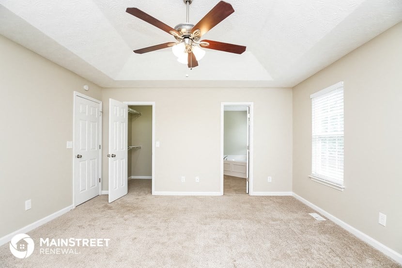 the master bedroom has a ceiling fan and a carpeted floor