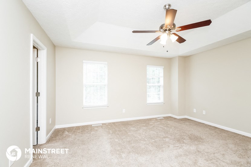 a living room with carpet and a ceiling fan