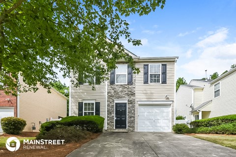 a white house with a garage door and a tree