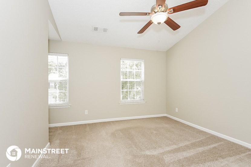 the master bedroom has a carpeted floor and a ceiling fan