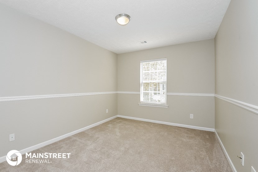a bedroom with white walls and carpet and a window