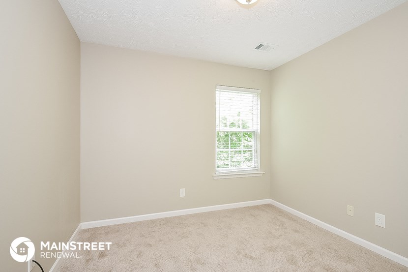 a bedroom with a carpeted floor and a window