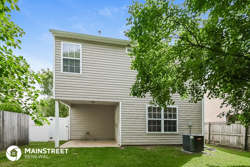 the backyard of a white house with a garage and a tree
