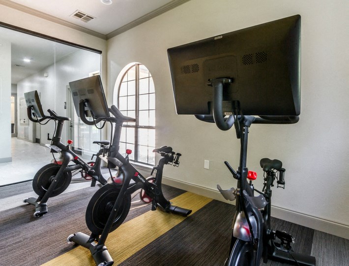 a workout room with exercise bikes and a tv
