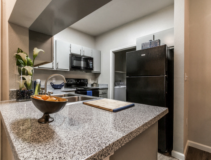 a kitchen with a granite counter top and a black refrigerator