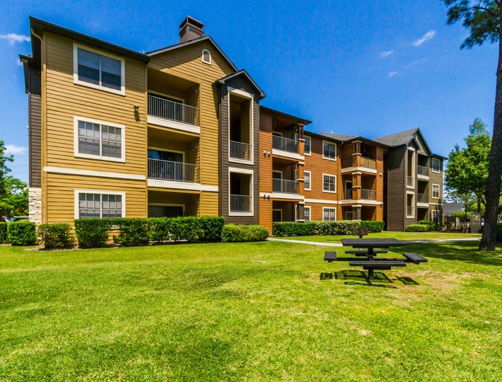 an apartment building with a picnic table in the grass