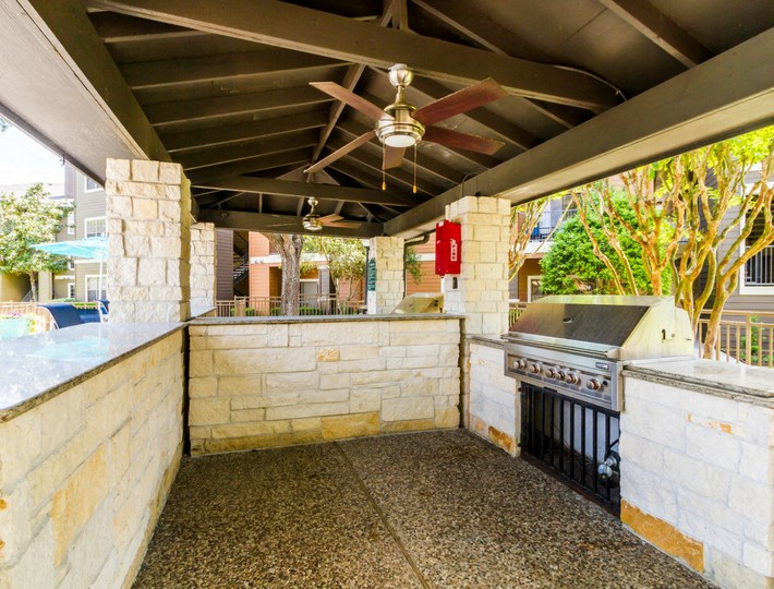 the outdoor kitchen has a grill and a counter with a sink