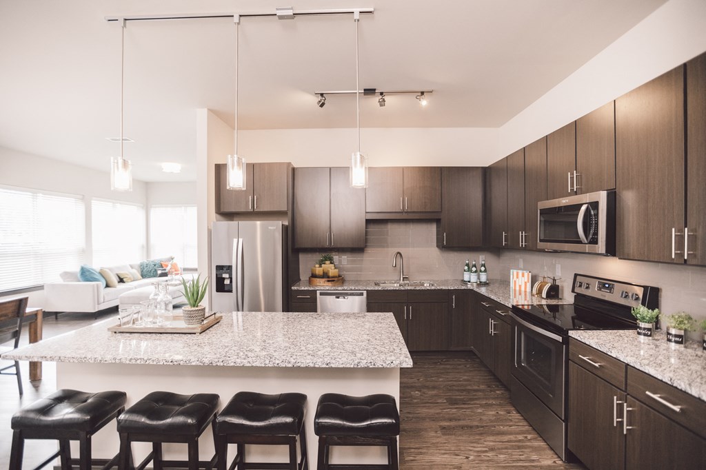 a large kitchen with a marble counter top and dark cabinets