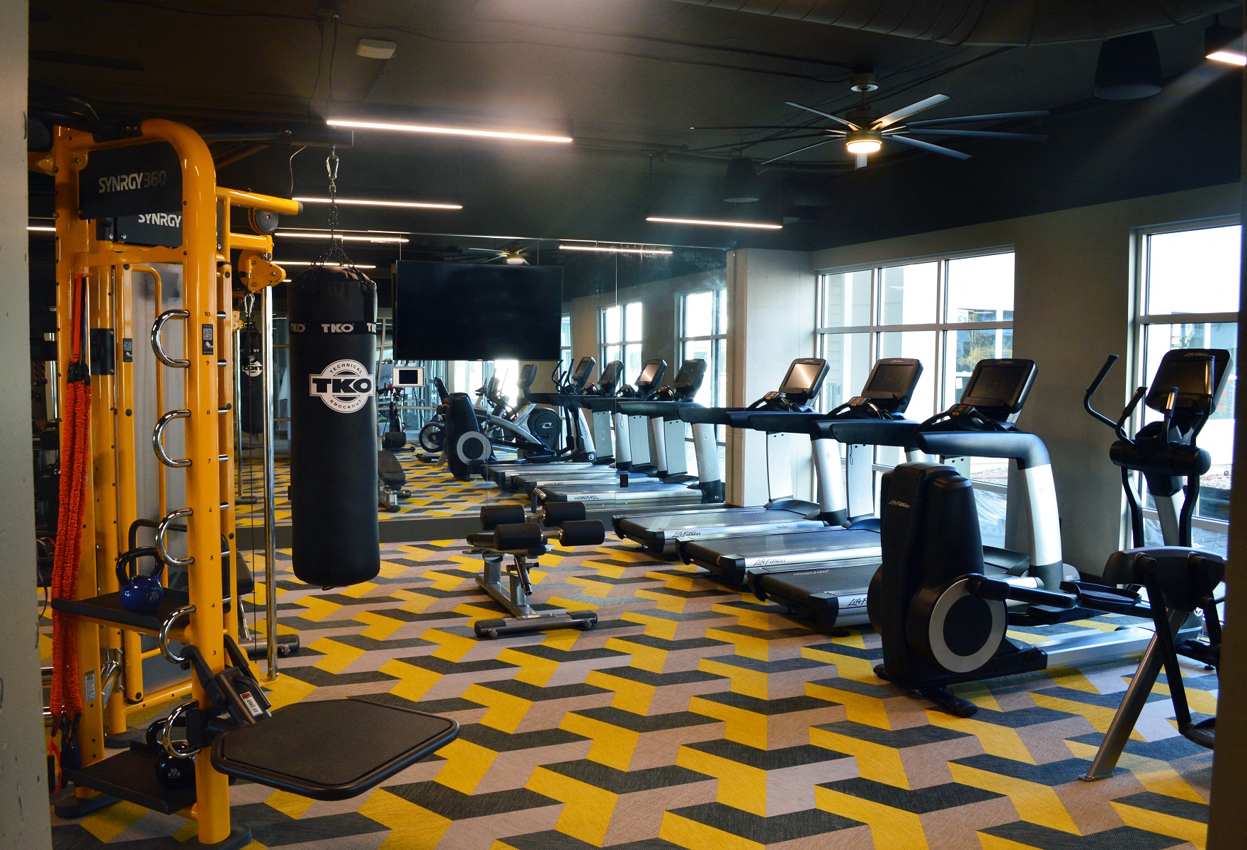 a gym with cardio equipment and weights on the floor