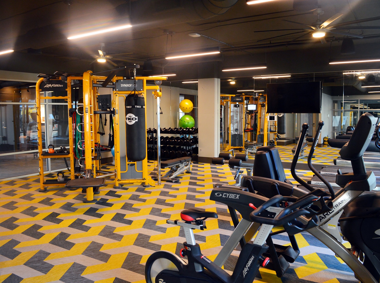a gym with cardio equipment and weights on the floor