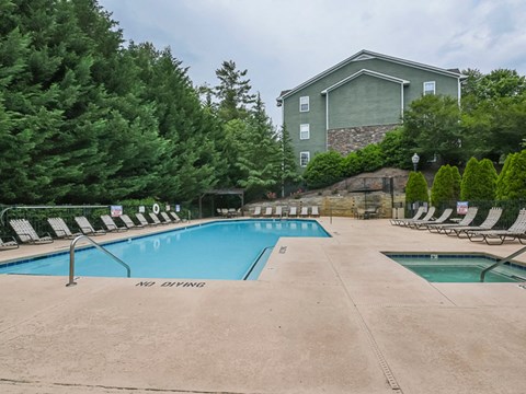 a swimming pool with chairs around it and a house in the background