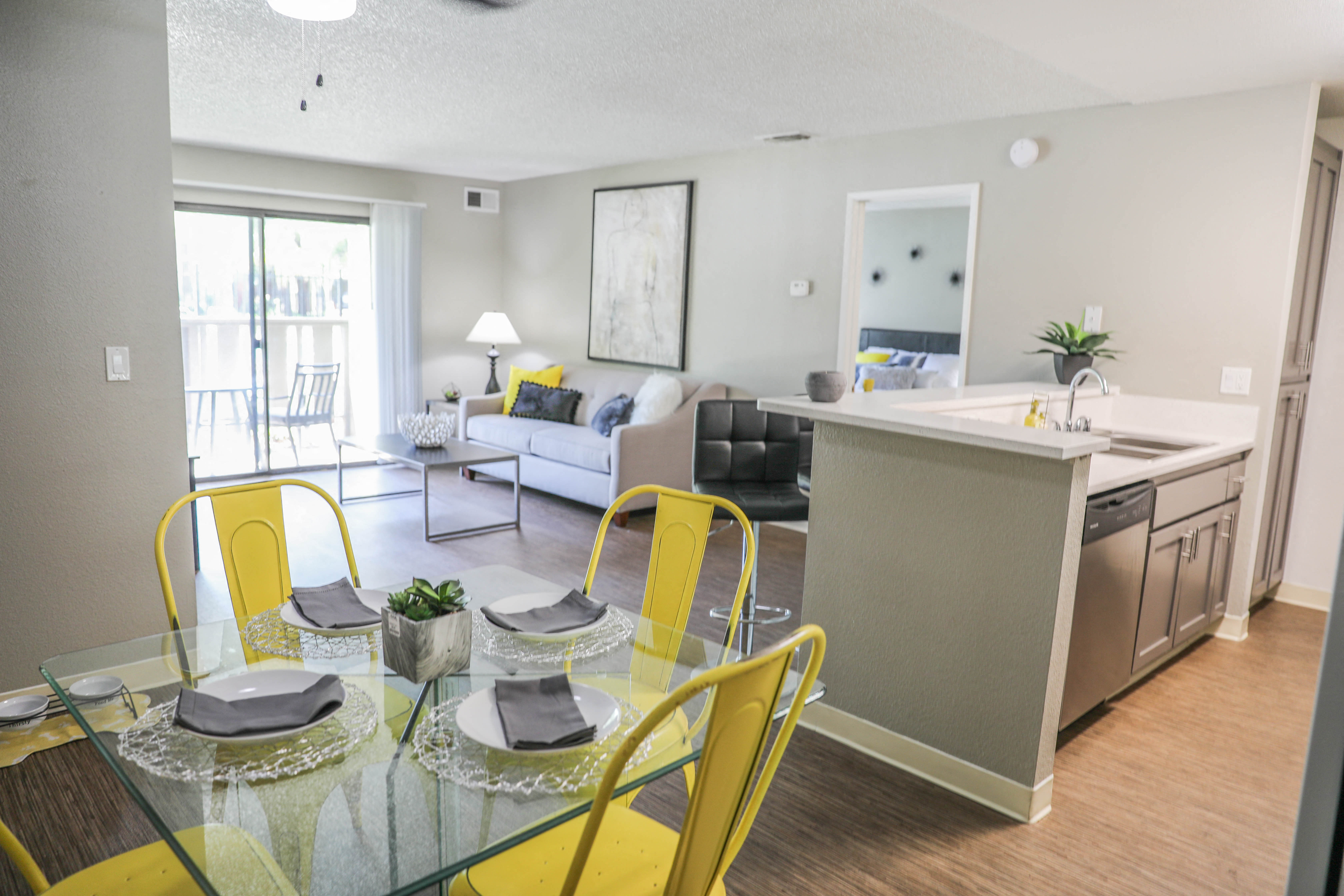 a living room and dining room with a glass table and yellow chairs