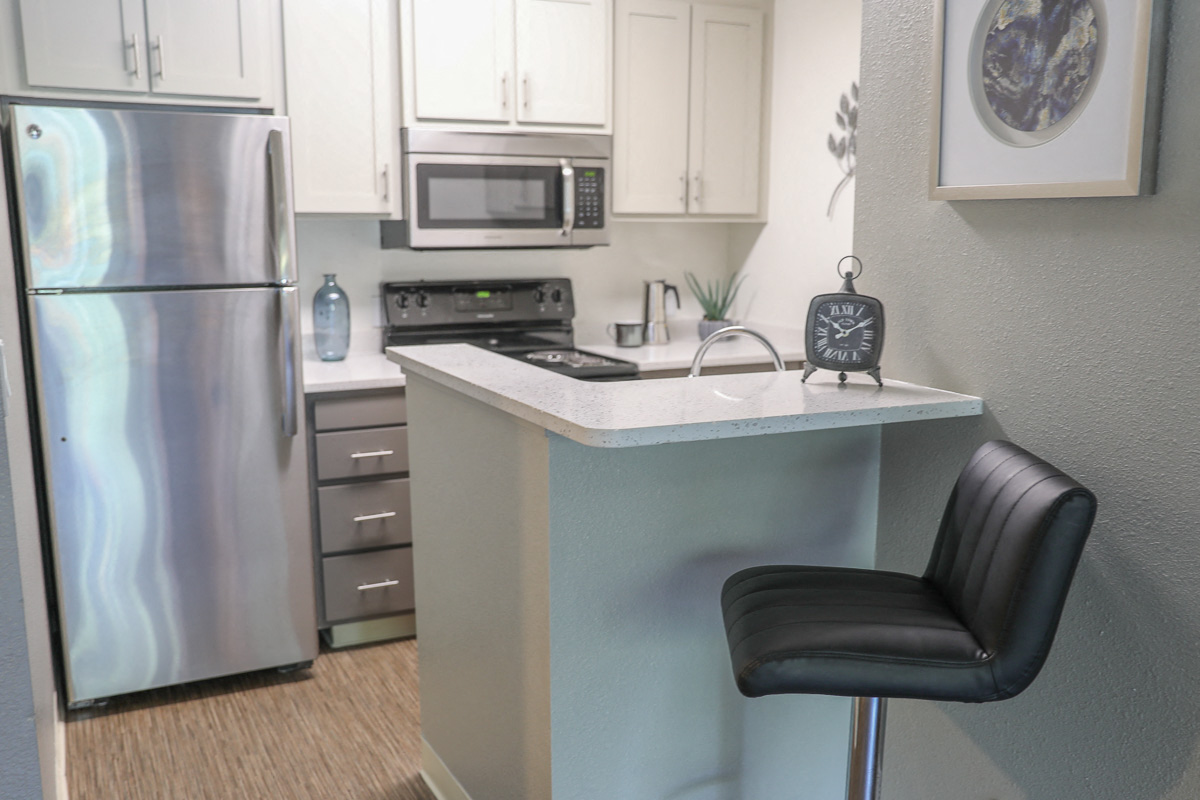 a kitchen with stainless steel appliances and a counter with a black chair