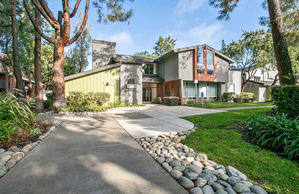 a house with a sidewalk and trees in front of it