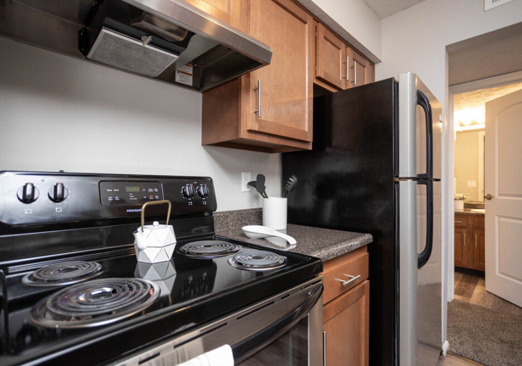 a kitchen with black appliances and wooden cabinets and a black stove