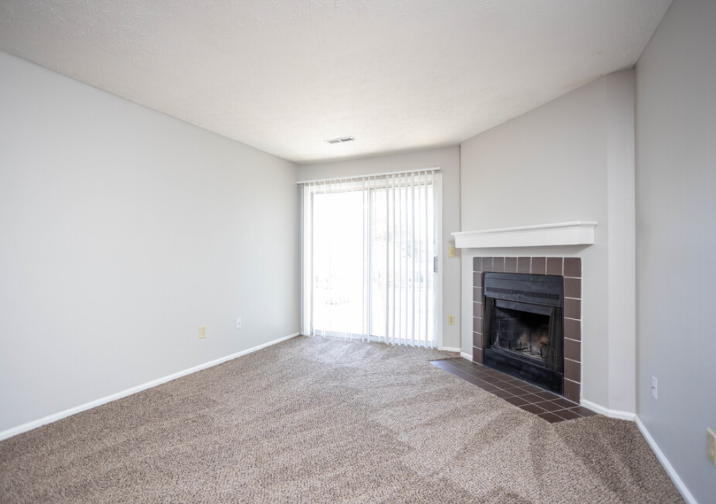 an empty living room with a fireplace and a window