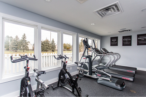 a home gym with bikes and windows overlooking a pond