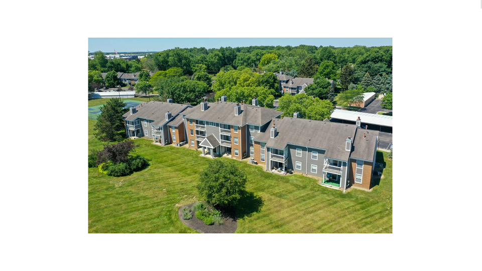 an aerial view of a house with a green lawn and trees