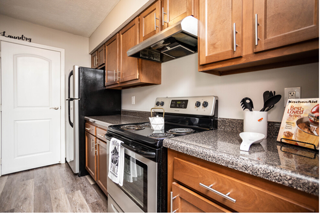 a kitchen with wood cabinets and black appliances and granite counter tops