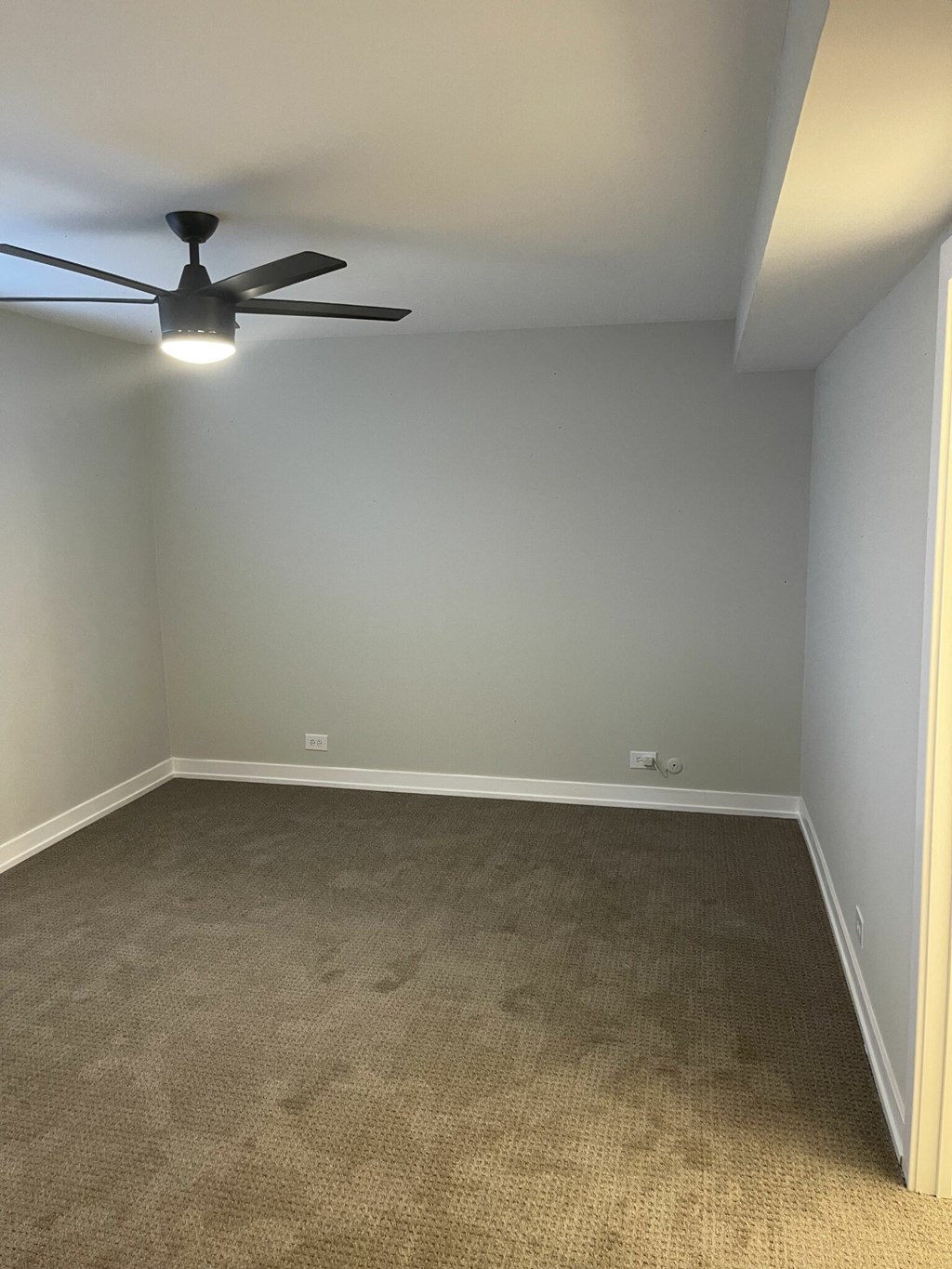 an empty room with a ceiling fan and carpet