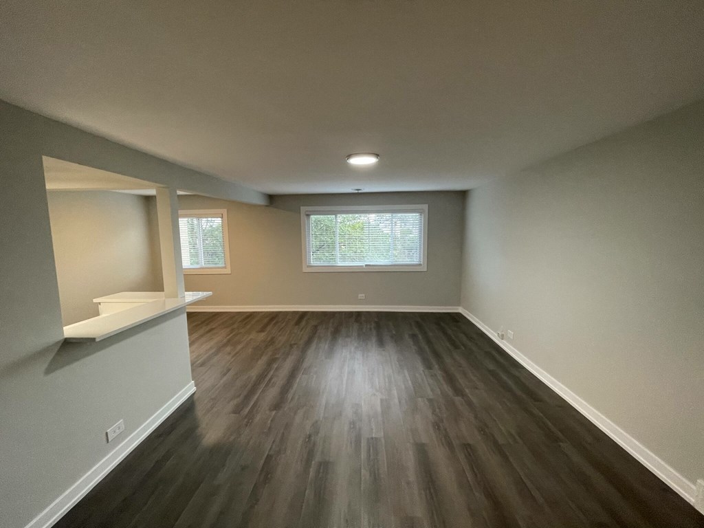 an empty living room with wood floors and a window