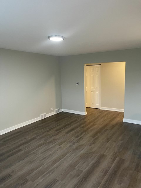 an empty living room with wooden floors and a white door