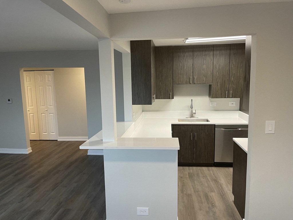 an empty kitchen with white countertops and wooden cabinets