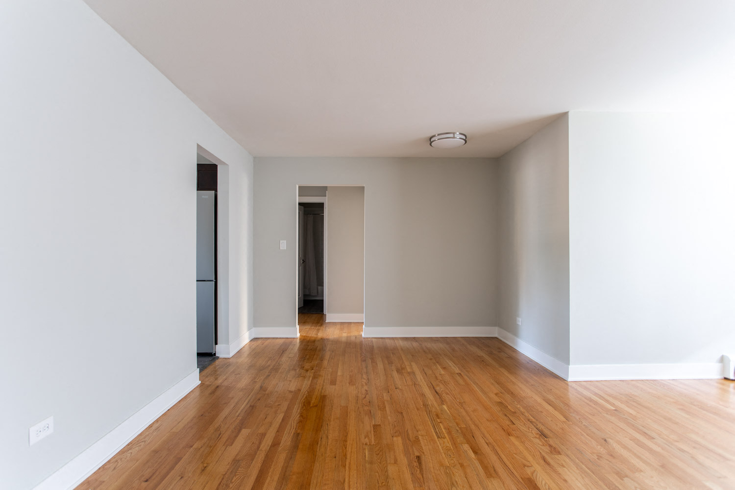 an empty living room with wood floors and white walls