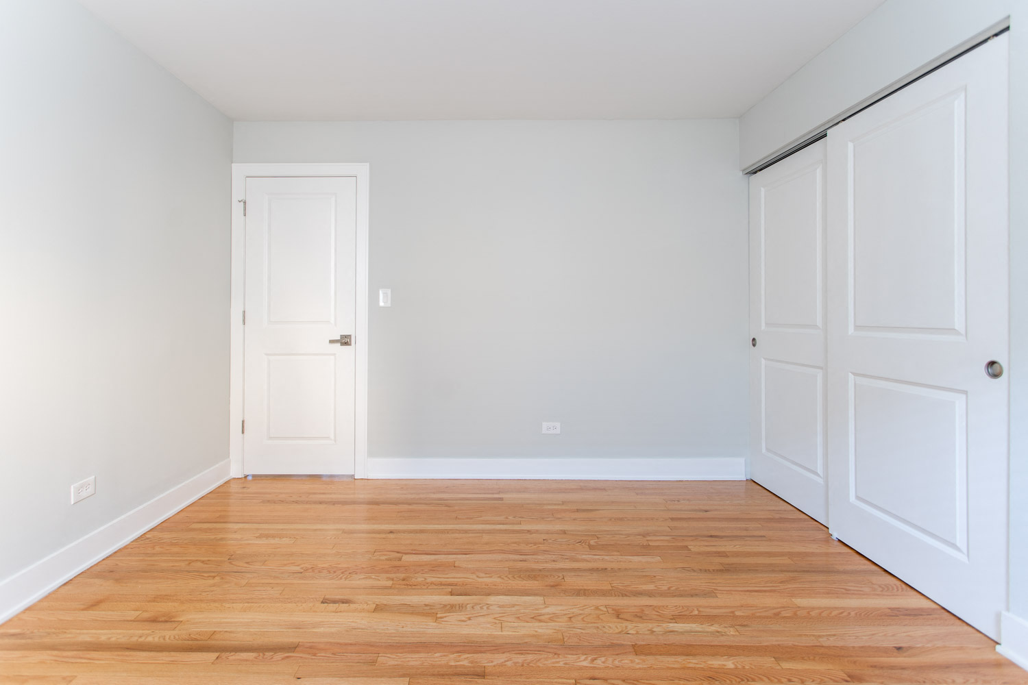an empty room with wood floors and white doors