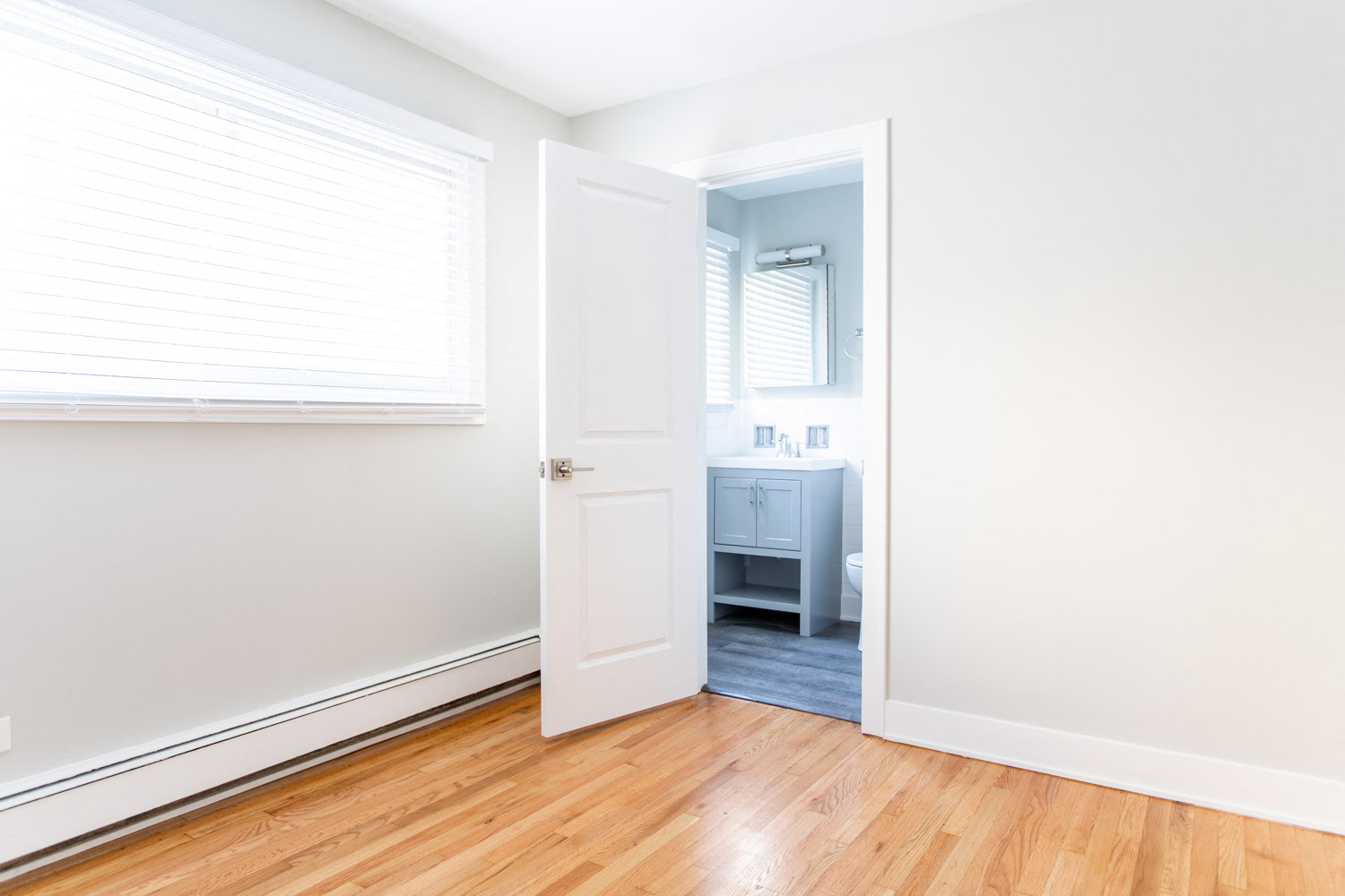 an empty bedroom with a door open to a bathroom