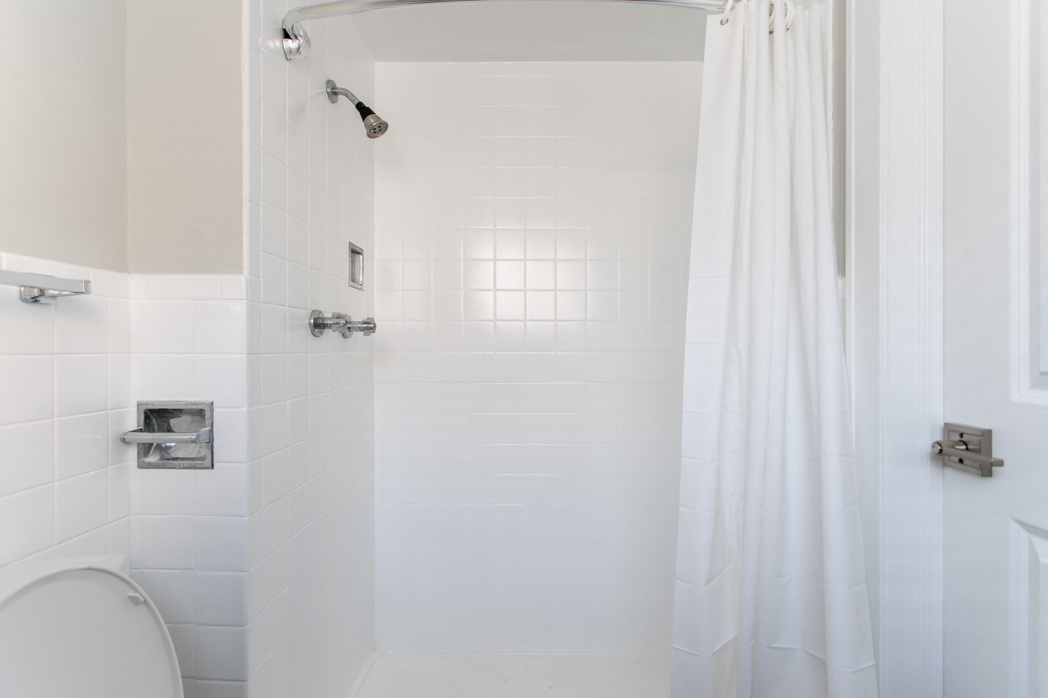 a white bathroom with a shower and a toilet