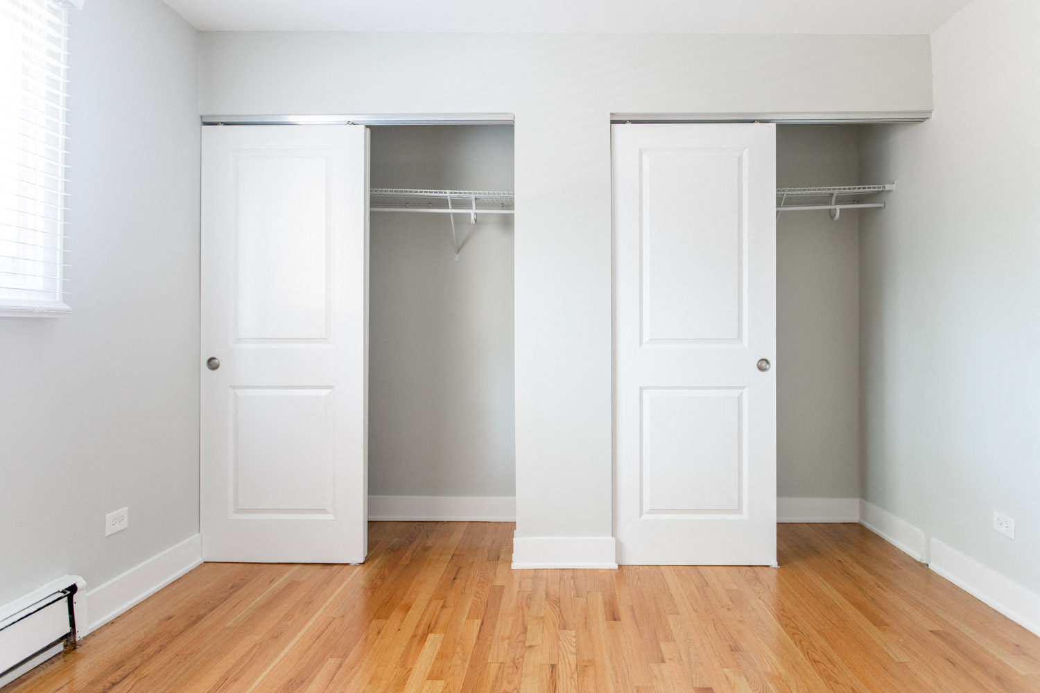 an empty bedroom with two closet doors and a wood floor