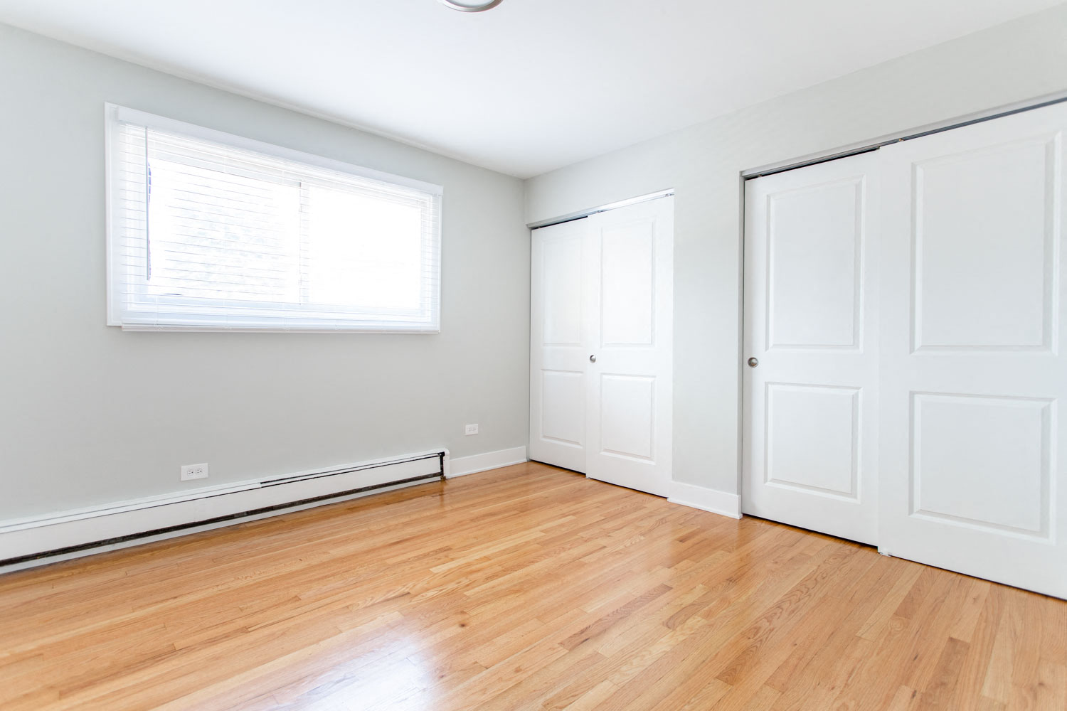 an empty room with wood floors and white doors