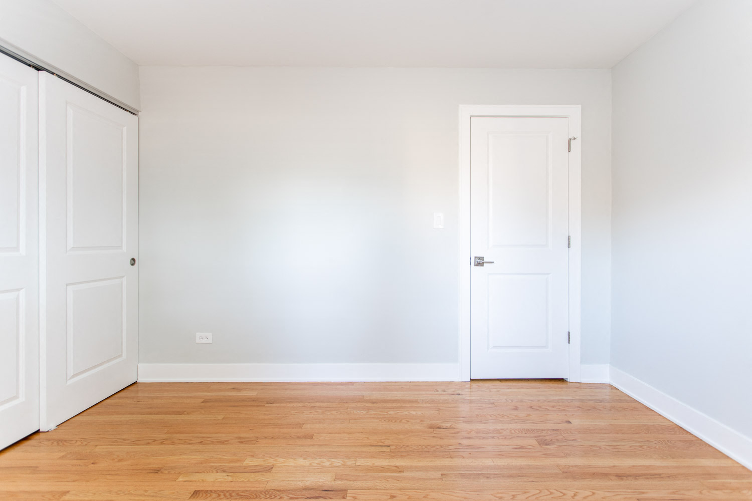 an empty room with white walls and a wood floor