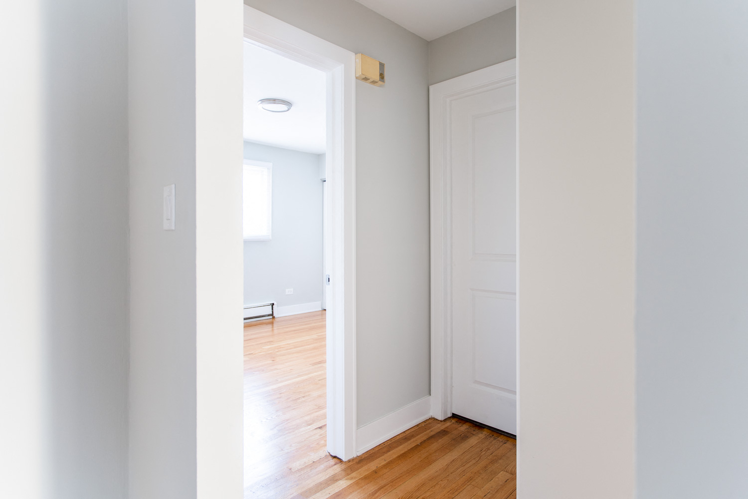 an empty room with a white door and a wood floor