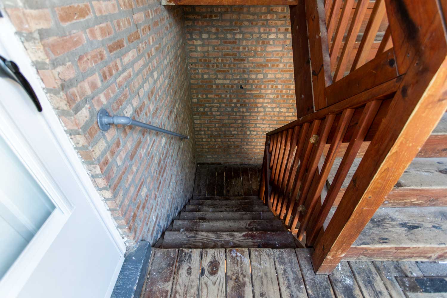 a stairwell with wooden stairs and brick walls