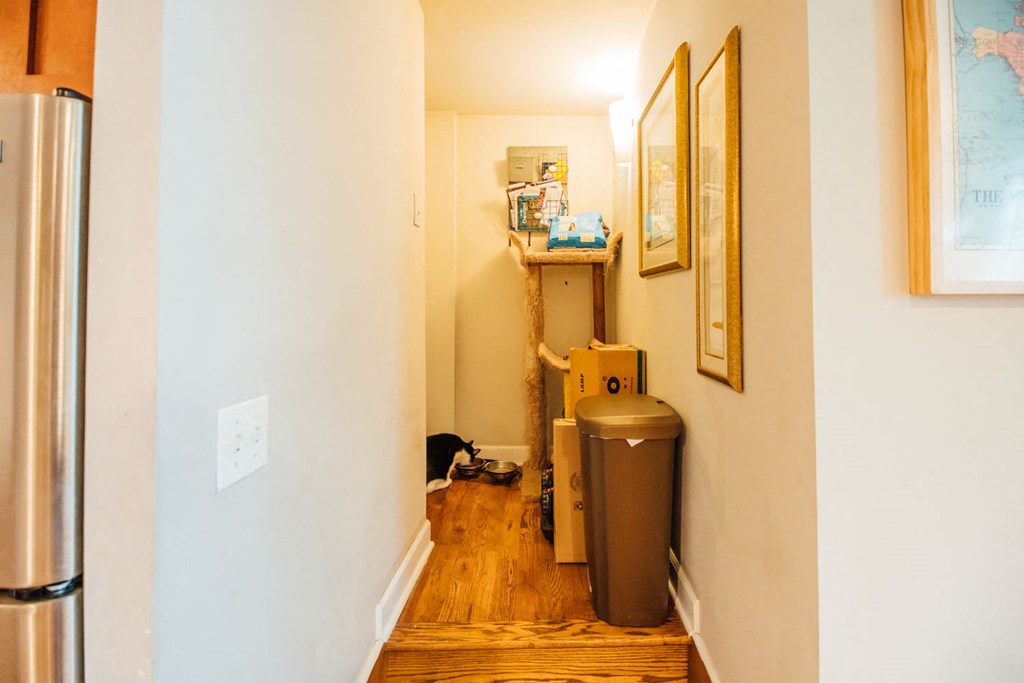 a small room with a trash can and a shelf on the wall