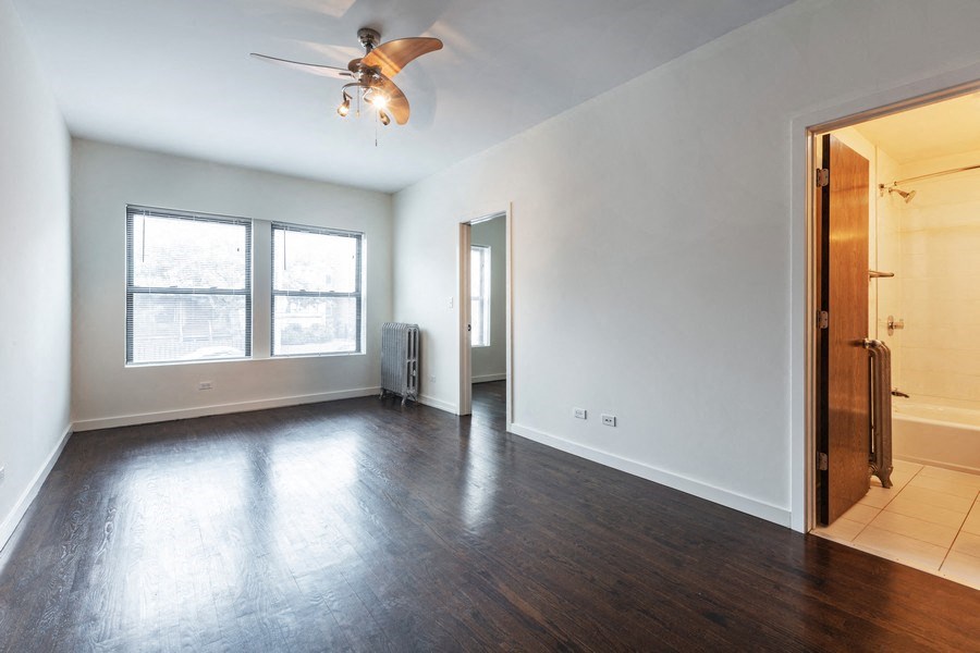 an empty living room with wood floors and a ceiling fan