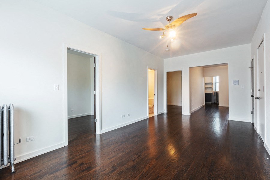 an empty living room with wood floors and a ceiling fan