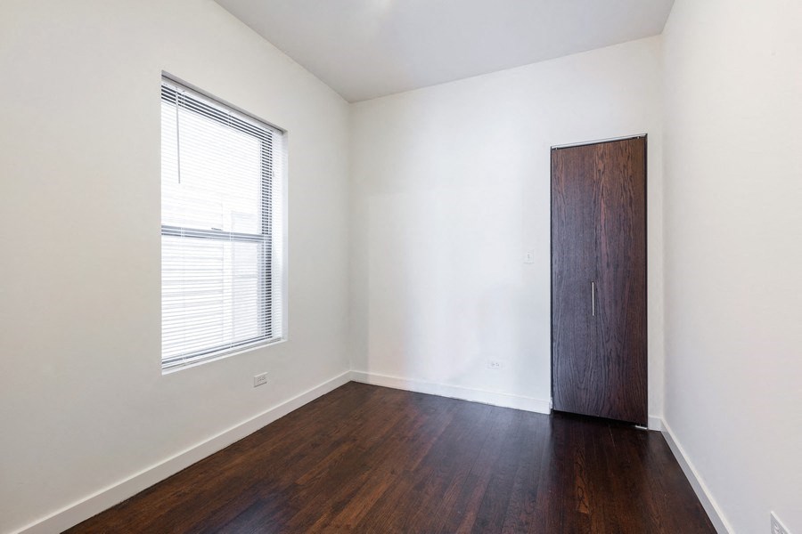 an empty room with wood floors and a window and a wooden door