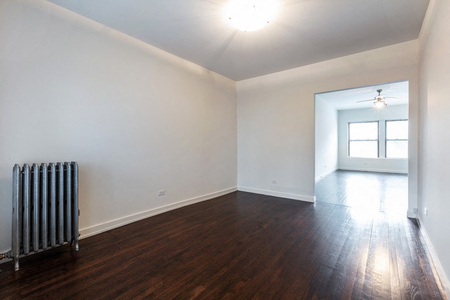 the living room and dining room of an empty house with a radiator