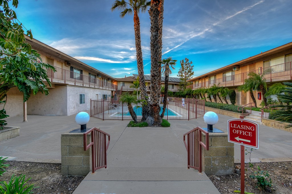 a building with a swimming pool and palm trees in front of it