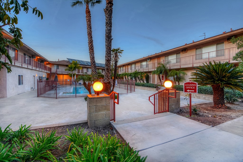 apartments with a pool and palm trees at dusk