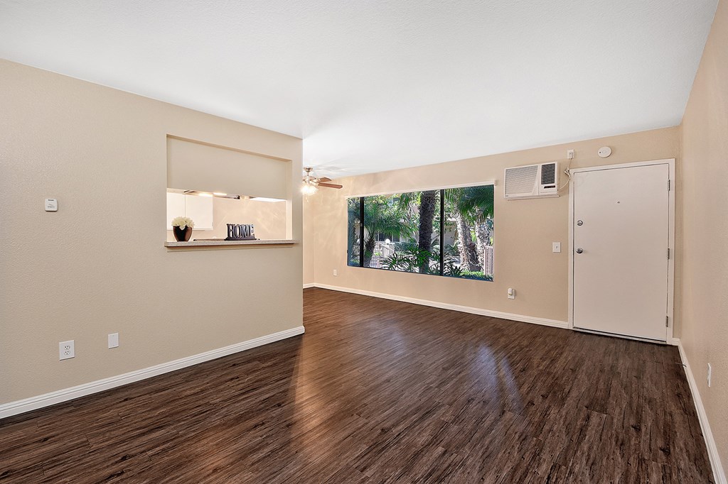 an empty living room with hard wood floors and a window