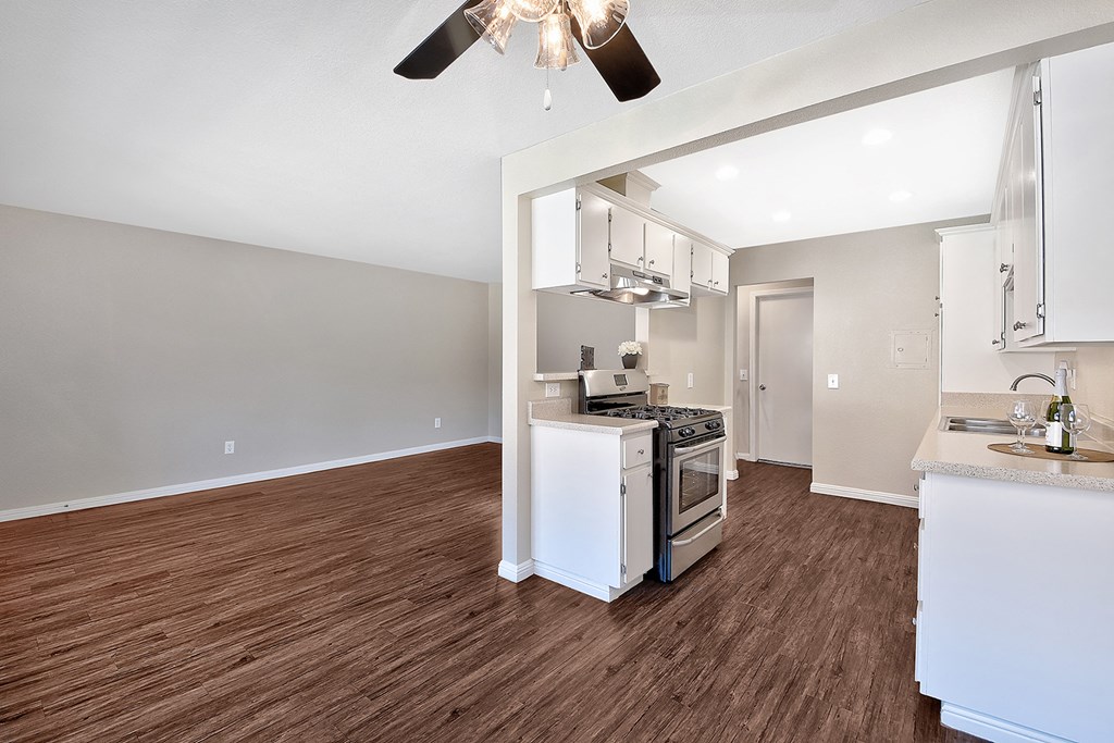 an open kitchen and living room with wood flooring and a ceiling fan