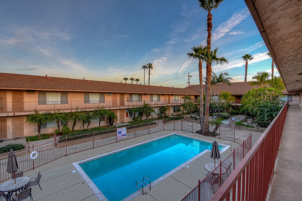 a pool is shown in the courtyard of a hotel with palm trees