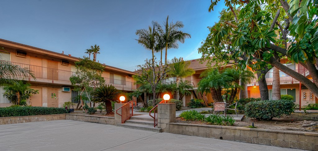 the courtyard of a hotel with palm trees and a sidewalk
