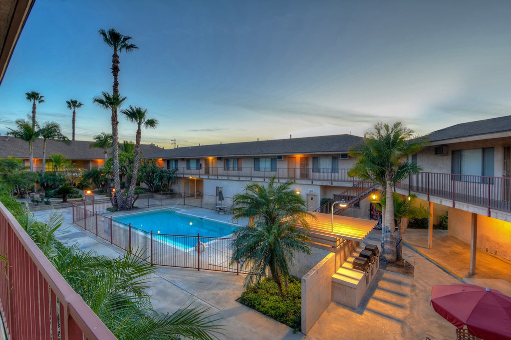 a building with a pool and palm trees at night