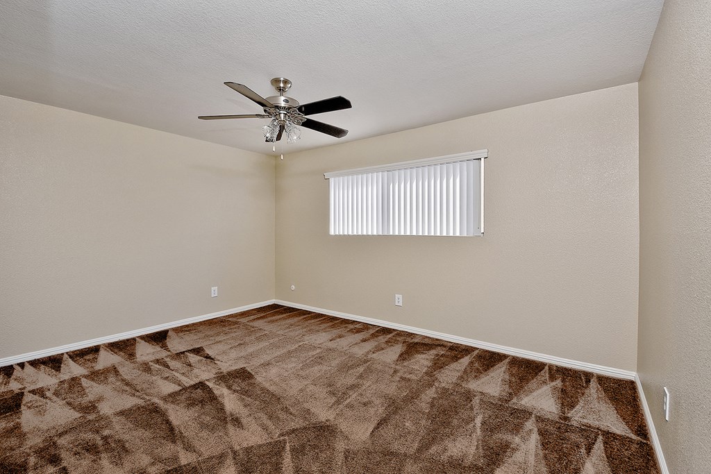 an empty living room with a ceiling fan and a window